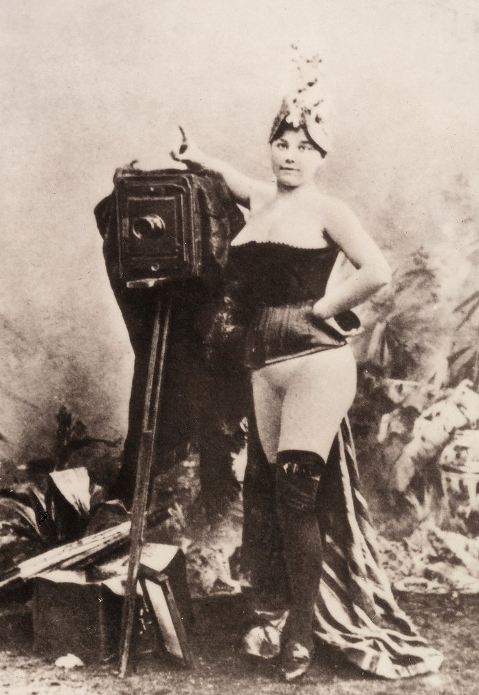 Egy antik fényképezőgépre támaszkodó, részben meztelen nő portréja. alkotó: Unknown photographer