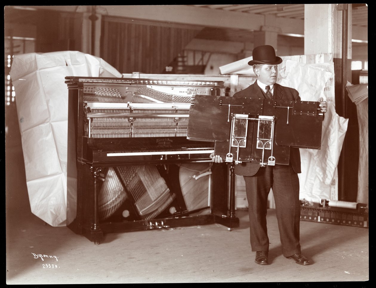 A Ricca and Son Piano Co. zongorája a mellette lévő férfival, aki a zongoraművek egy részét feltartja, 1907 (ezüstzselatin nyomat) alkotó: Byron Company