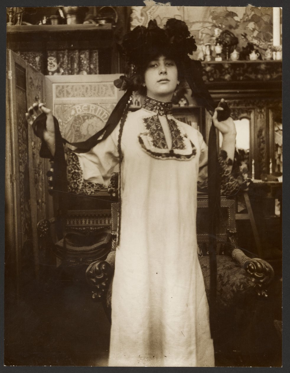 [Női modell hosszú fehér köntösben és szalagokkal díszített kalapban, Párizs] alkotó: Alphonse Maria Mucha