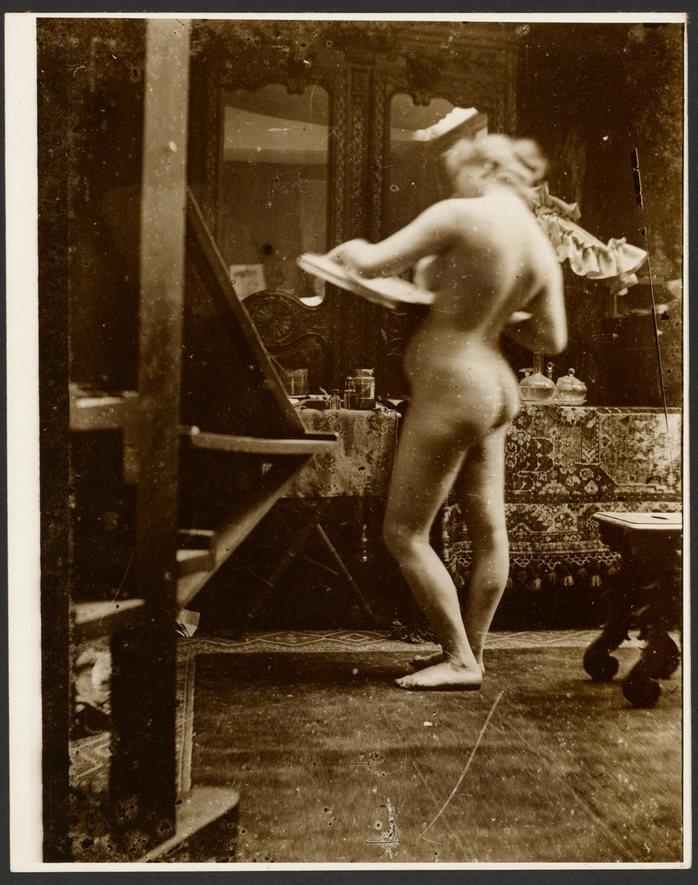 [Női aktmodell áll a stúdióban, kezében egy vázlatfüzettel] alkotó: Alphonse Maria Mucha