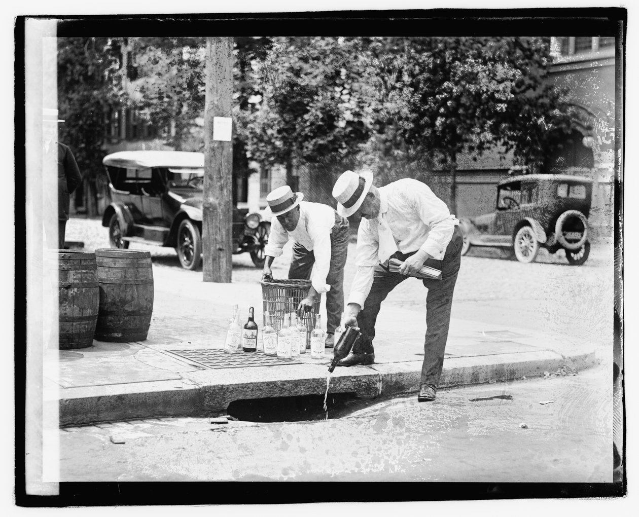 Két férfi szeszesitalt tölt a csapadékcsatornába, 1921. július 8. (f/w fotó) alkotó: American Photographer