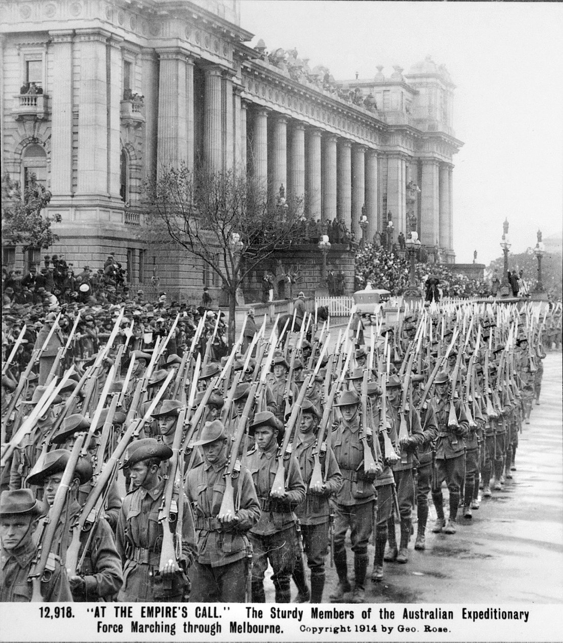 A tengerentúli hadsereg katonái vonulnak el a Parlament mellett Melbourne-ben, Vicben, puskáik, szuronyokkal a vállukon, mielőtt tengerentúli szolgálatra indulnak, 1914. augusztus körül. alkotó: Australian Photographer
