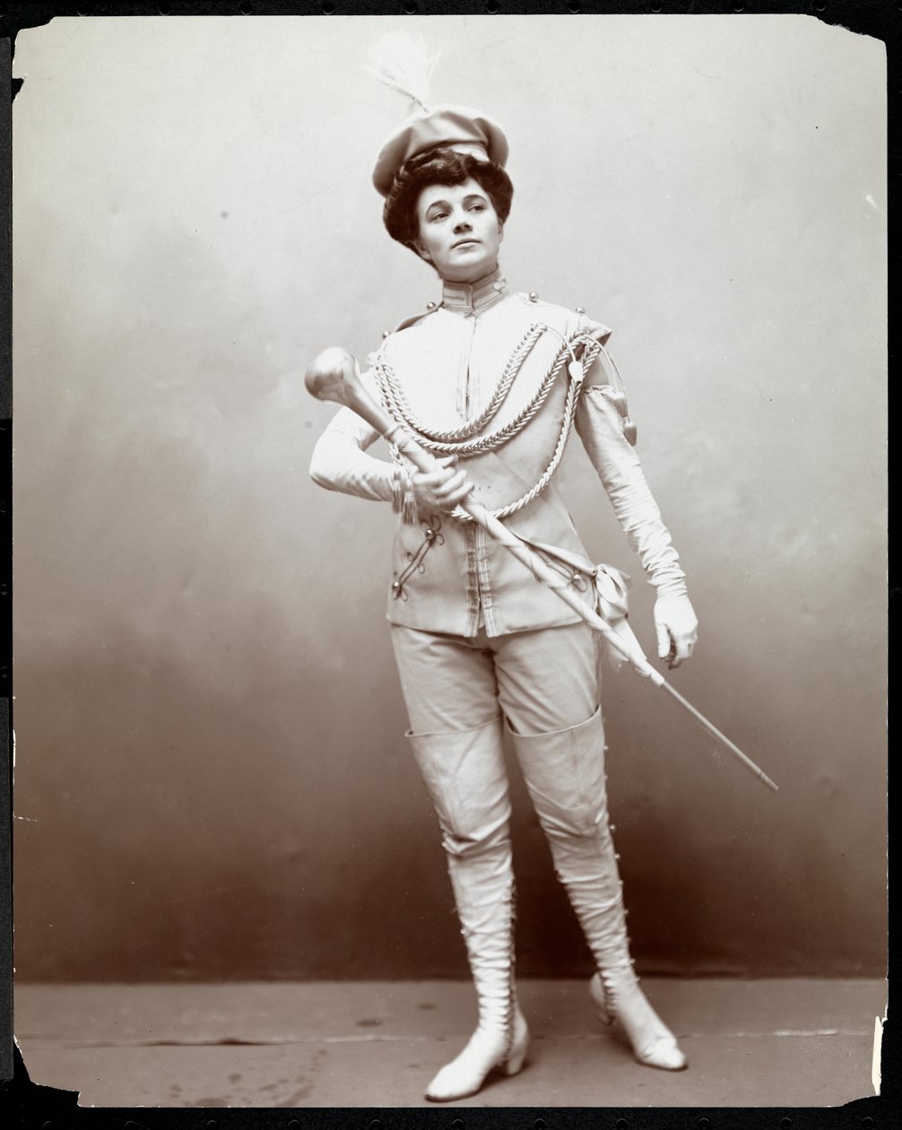 Egy nő zenekari egyenruhát modellező, bottal a kezében, 1898 körül (ezüst zselatin nyomat) alkotó: Byron Company