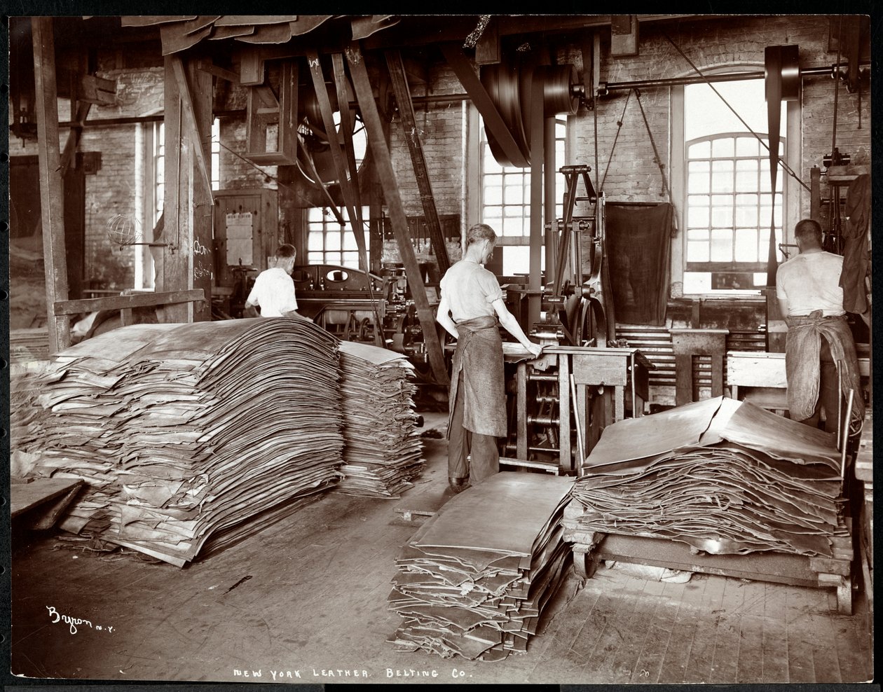 Belső nézet három férfiról, aki bőrrel és nehéz felszerelésekkel dolgozik a New York-i Leather Belting Co.-nál, New York, 1905 (ezüst zselatin nyomat) alkotó: Byron Company