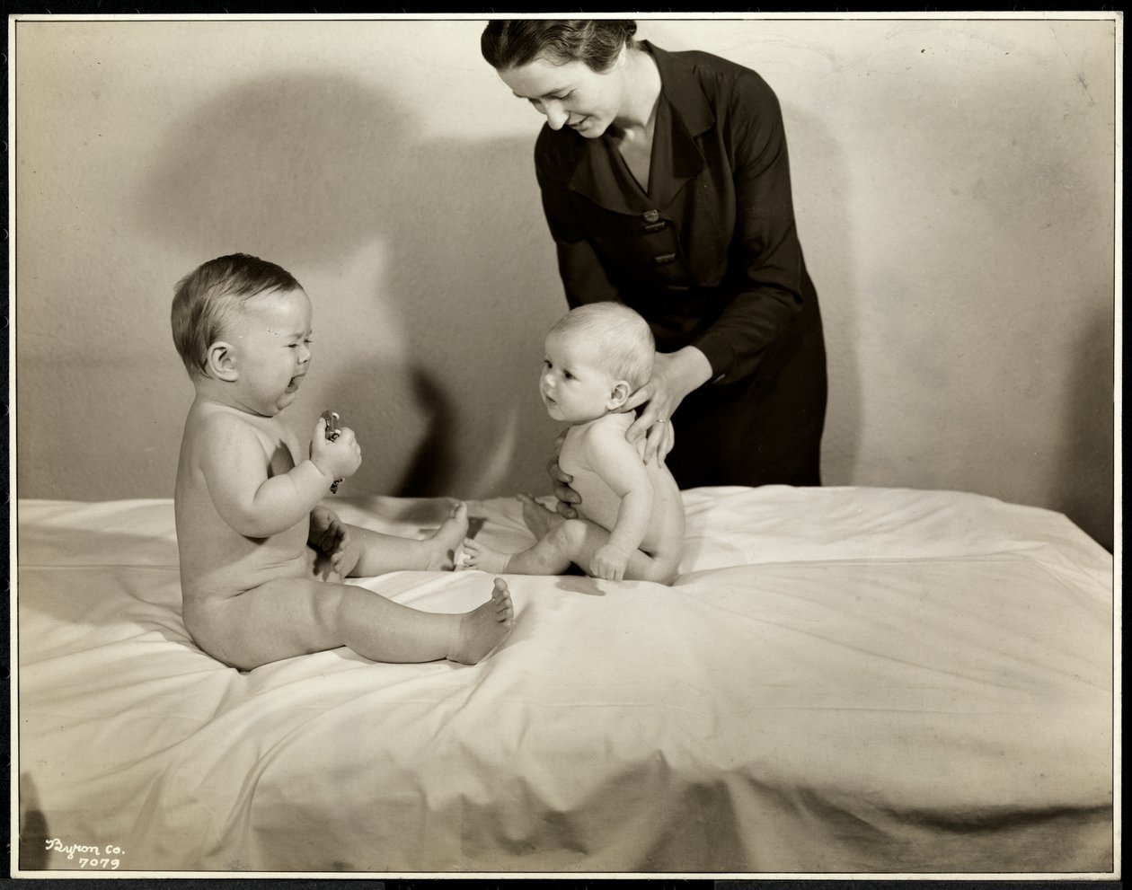 Két csecsemő ül az ágyban, az egyiket egy nővér támogatja, a másik egy játékautót tart, és sír a Maternity Center Association-ben, a 70th Street East River, New York-ban, 1935 (ezüst zselatin nyomat) alkotó: Byron Company