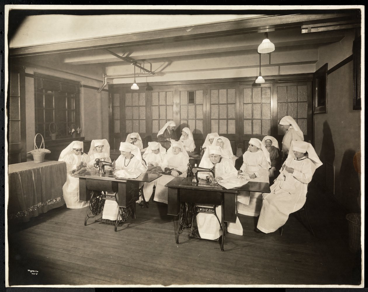 Fehér köpenyt viselő nők egy varrótanfolyamon, feltehetően az I. világháború alatt vagy azzal összefüggésben, New York, 1920 körül (ezüstzselatinos nyomat) alkotó: Byron Company