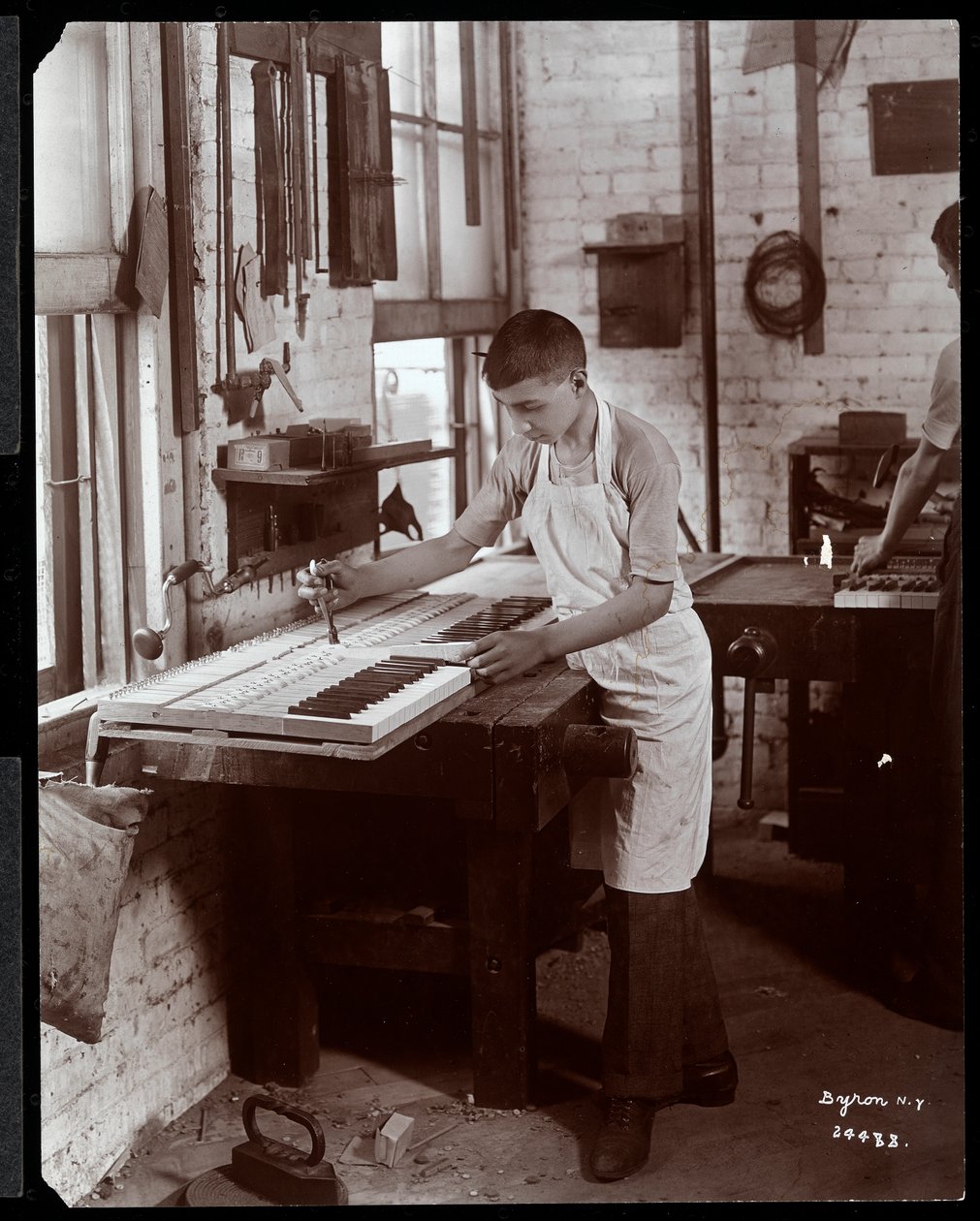 Egy fiatalember dolgozik a Harrington Piano Co. gyárban, 1907 (ezüstzselatinos nyomat) alkotó: Byron Company