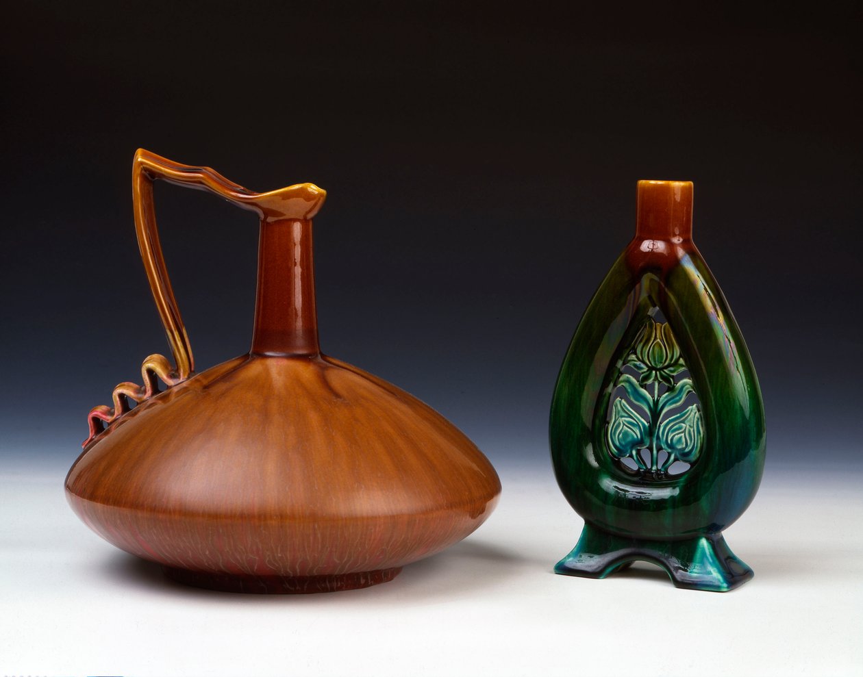 Összenyomott gömb alakú Linthorpe kerámiakancsó csíkos karamell, zöld és bíbor mázzal, valamint Linthorpe Pottery váza áttört virágbimbó díszítéssel és foltos zöld, kék és barna mázzal alkotó: Christopher Dresser