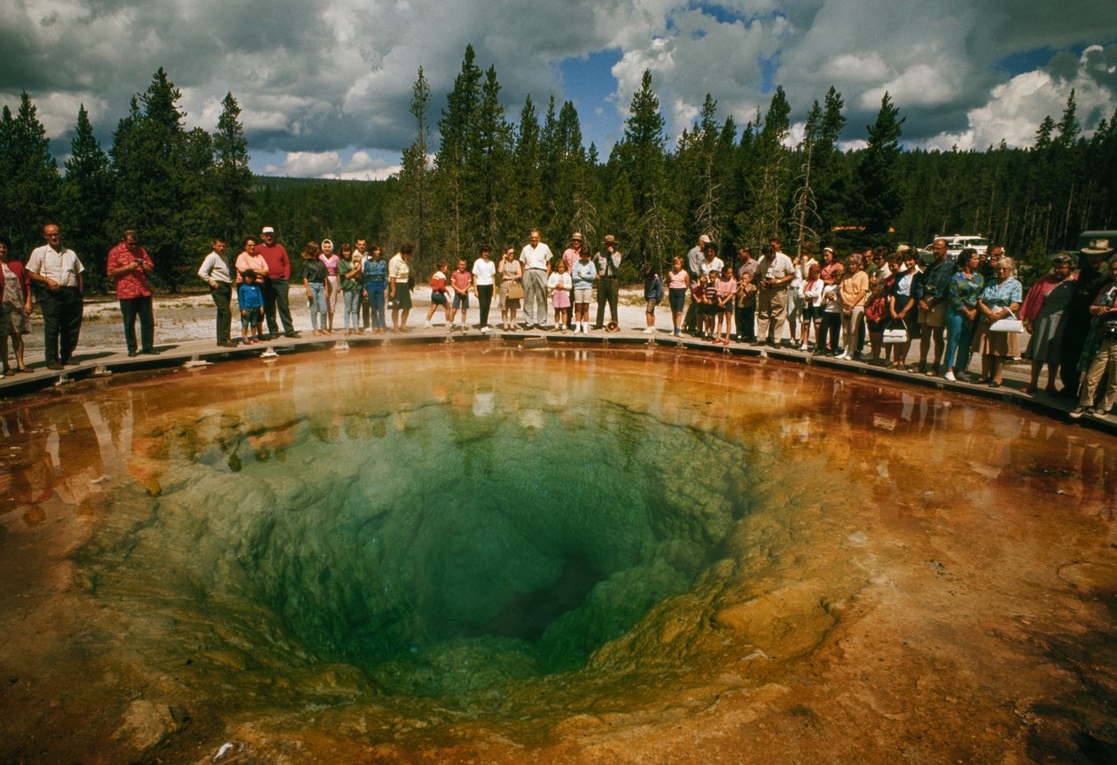 A park látogatói a kékeszöld, virág alakú termálmedence körül gyülekeznek. Yellowstone Nati... alkotó: Dean Conger