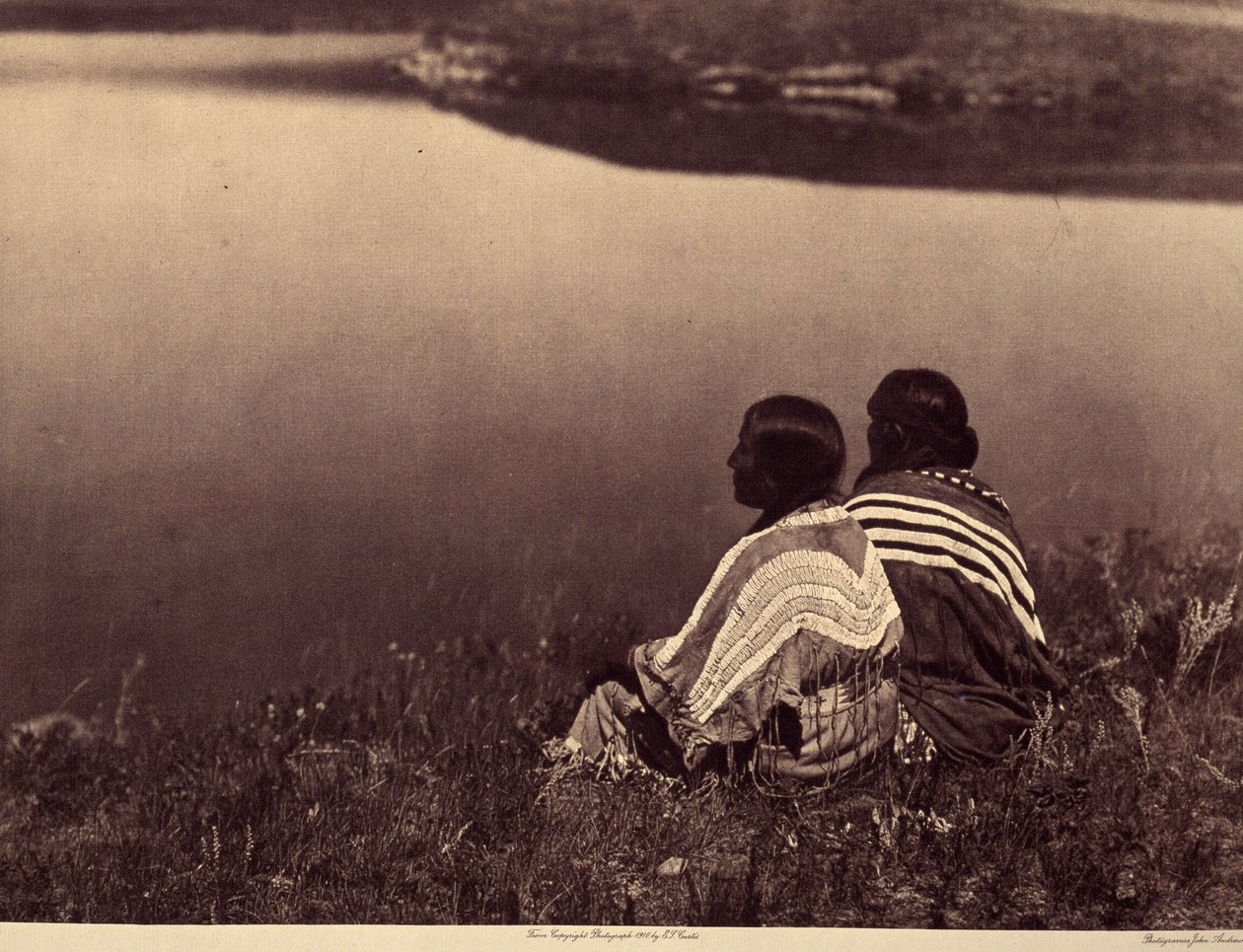 Egy tétlen óra – Egy pillanatnyi nyugalom: Piegan indiánok ülnek egy vízparton. A kép az Edward S. Curtis (1868-1952) által az észak-amerikai indiánokról szóló enciklopédiának 6. kötetéből készült, Theodore Roosevelt előszavával. B alkotó: Edward Sheriff Curtis