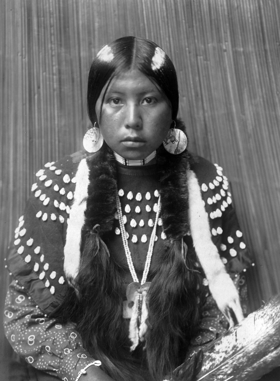 Kalispel indián nő, hajra festett fehér csíkok, kagylókorongos fülbevaló, jávorszarvasfogakkal díszített takaróruhát visel, kb. 1910, fotó Edward S. Curtis alkotó: Edward Sheriff Curtis