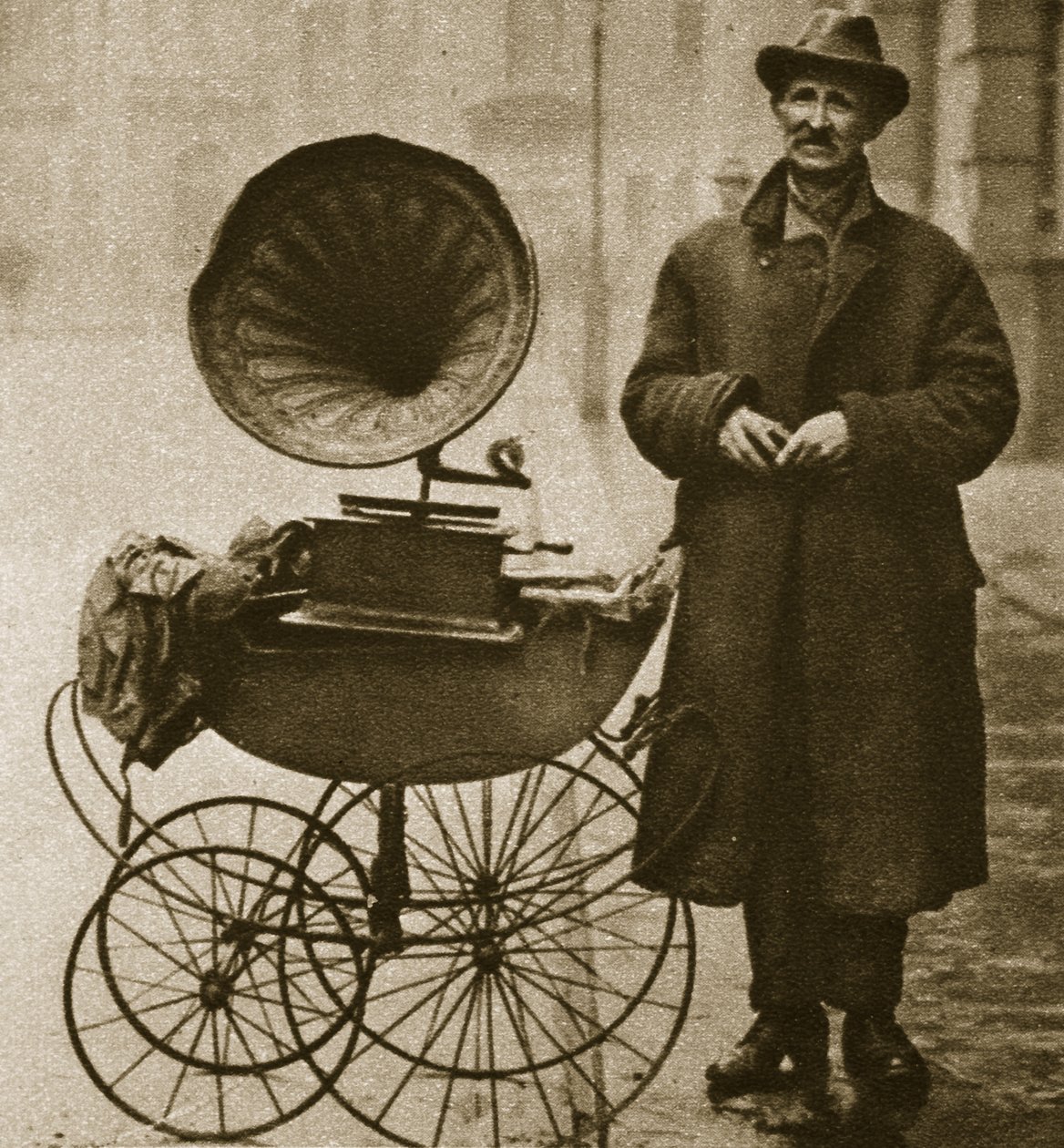 Egy utcai hawker gramofonnal szórakoztat, babakocsiban szállítják (szépia fotó) alkotó: English Photographer