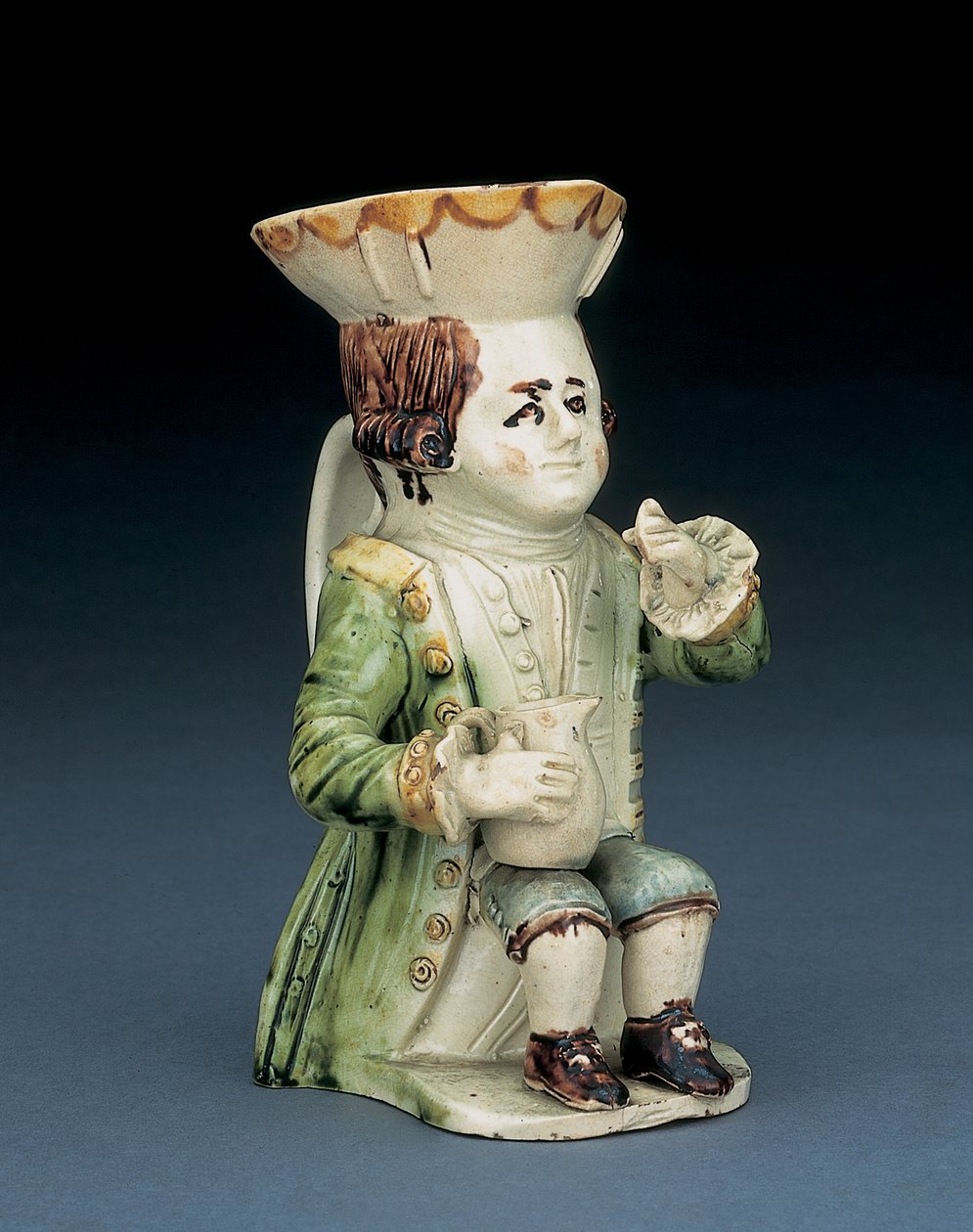Top toby kancsó, kalapja barna és sárga csipkés széllel, bekarcolt barna haja sorban áll, fehér rozettával a térdén baluszterkannával, 1770 körül alkotó: English School