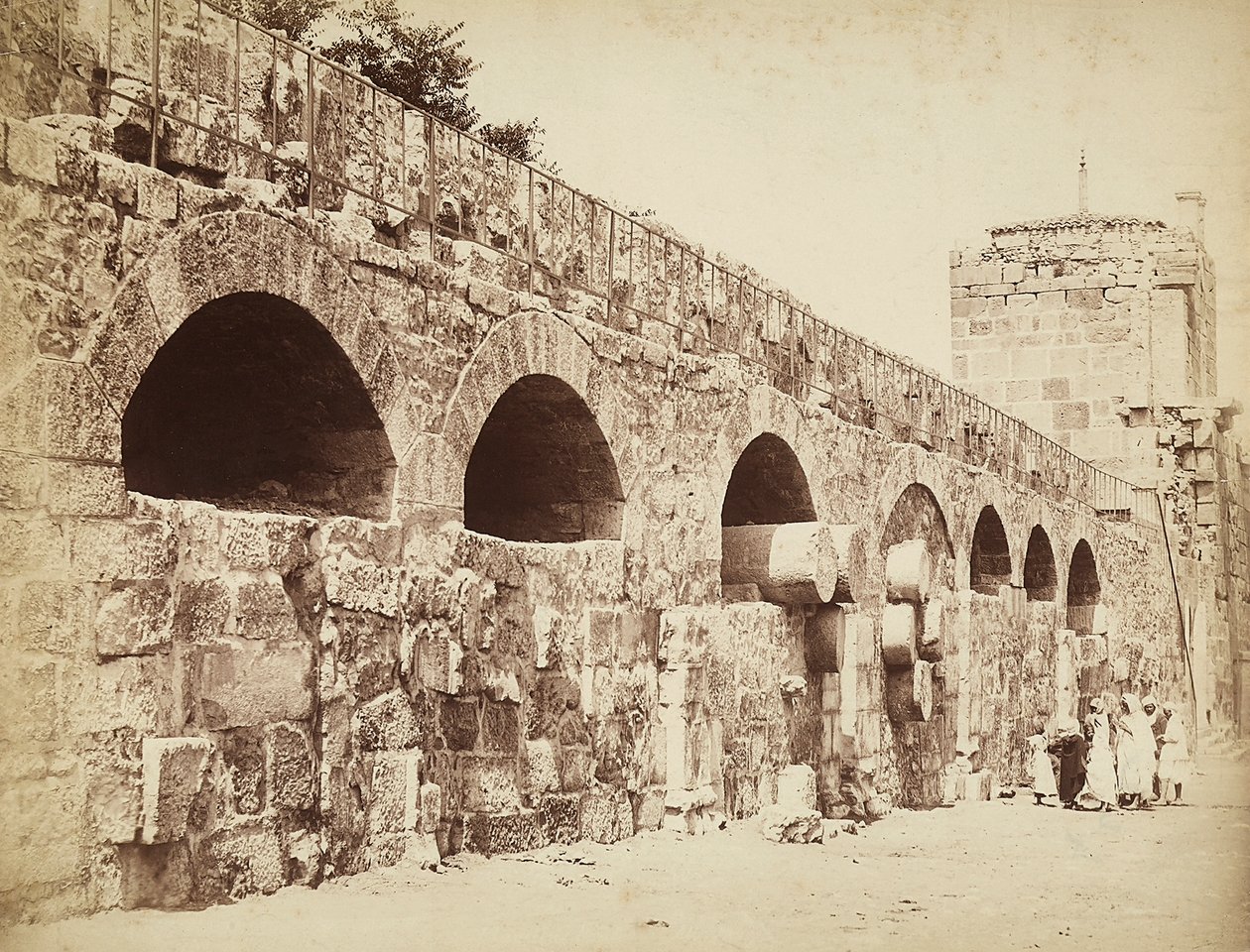 Kilátás Heliopolis vagy Baalbek városfalaira, az ősi szíriai városra, jelenleg Libanonra. Egy csoport ember gyűlt össze a fal közelében alkotó: Félix Bonfils