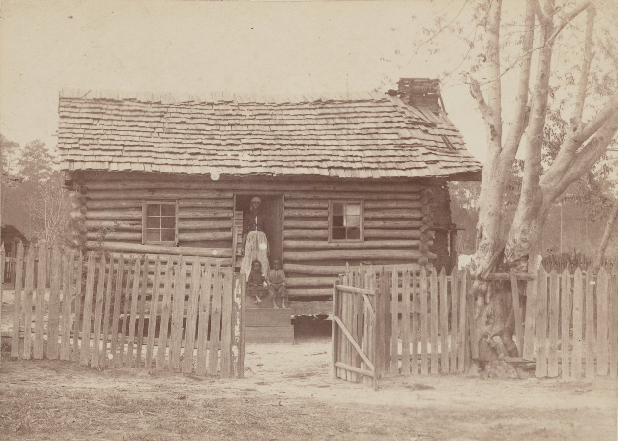 Albumen nyomat egy nőről és két gyerekről egy rönkház előtt Georgiában, 1880-as években. alkotó: H. S. Clark