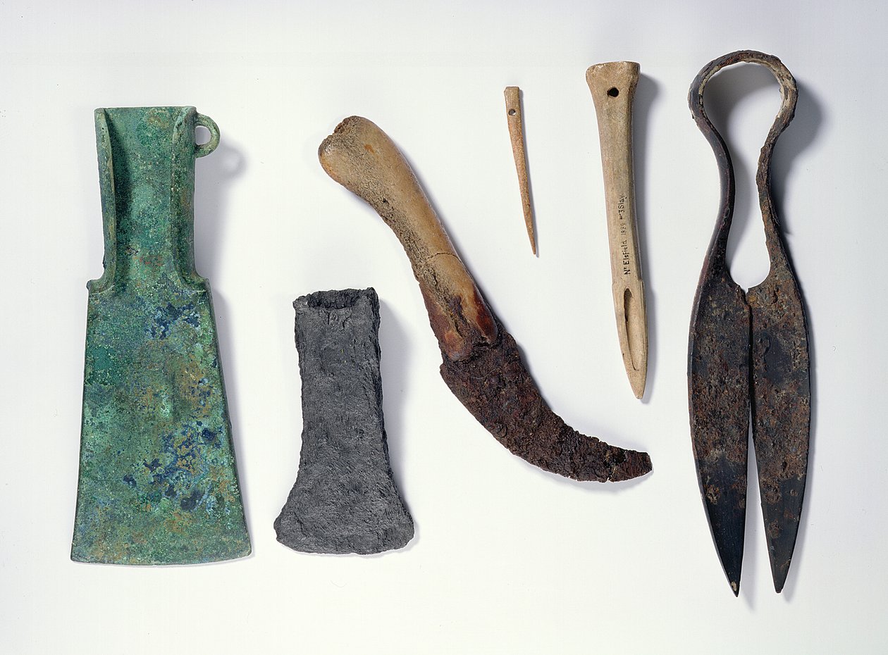 Az eszközök kiválasztása: L-R: kora vaskori bronz fejsze hajlított szárnyakkal; későbbi vasfejsze; csontnyéllel ellátott kés; csonttű; csontszegély; csontfűző; vasolló. alkotó: Iron Age