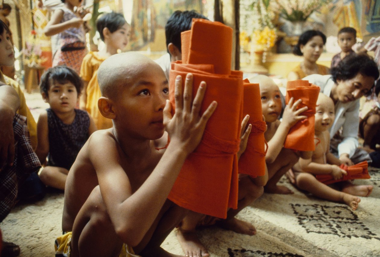 Egy fiatal fiú borotvált fejjel megkapja szerzetesi ruháját. Mandalay, Burma. alkotó: James L Stanfield