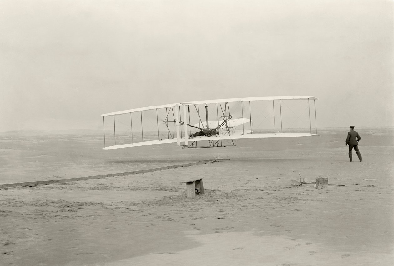 A Wright Flyer I első 120 láb magas repülését 12 másodperc alatt teszi meg az észak-karolinai Kitty Hawkban alkotó: John T. Daniels