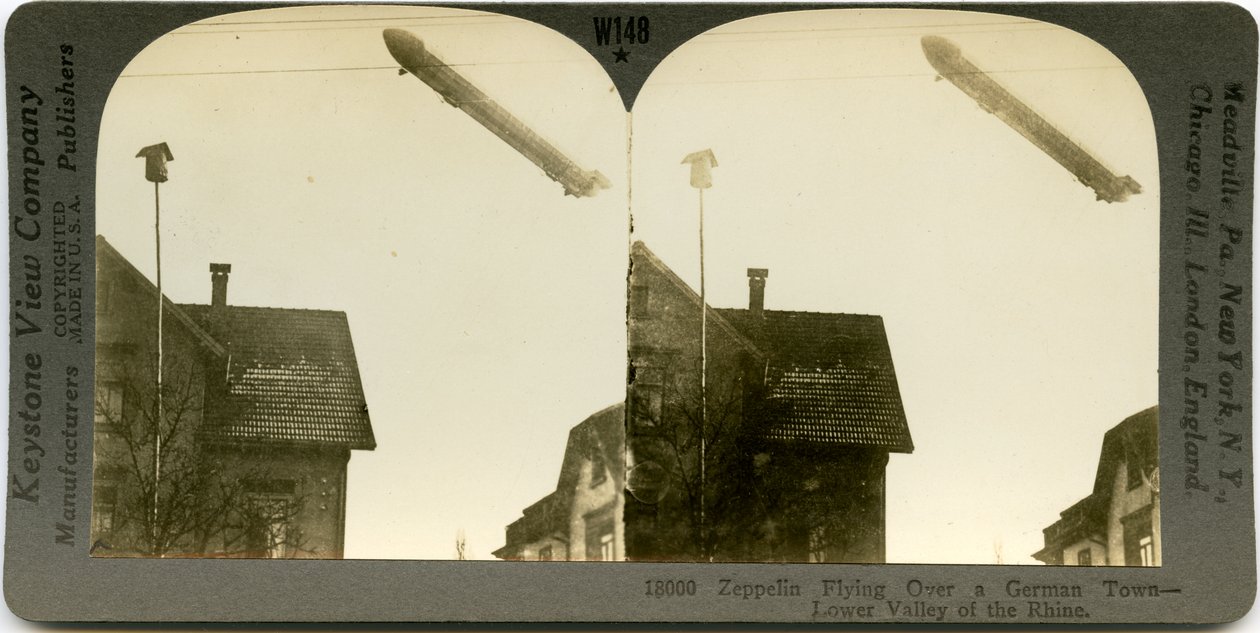 Vízszintes, szépia sztereokártya, amely egy Zeppelin repül a város tetején. Keystone Stereograph 18000. A cím így szól alkotó: Keystone View Company