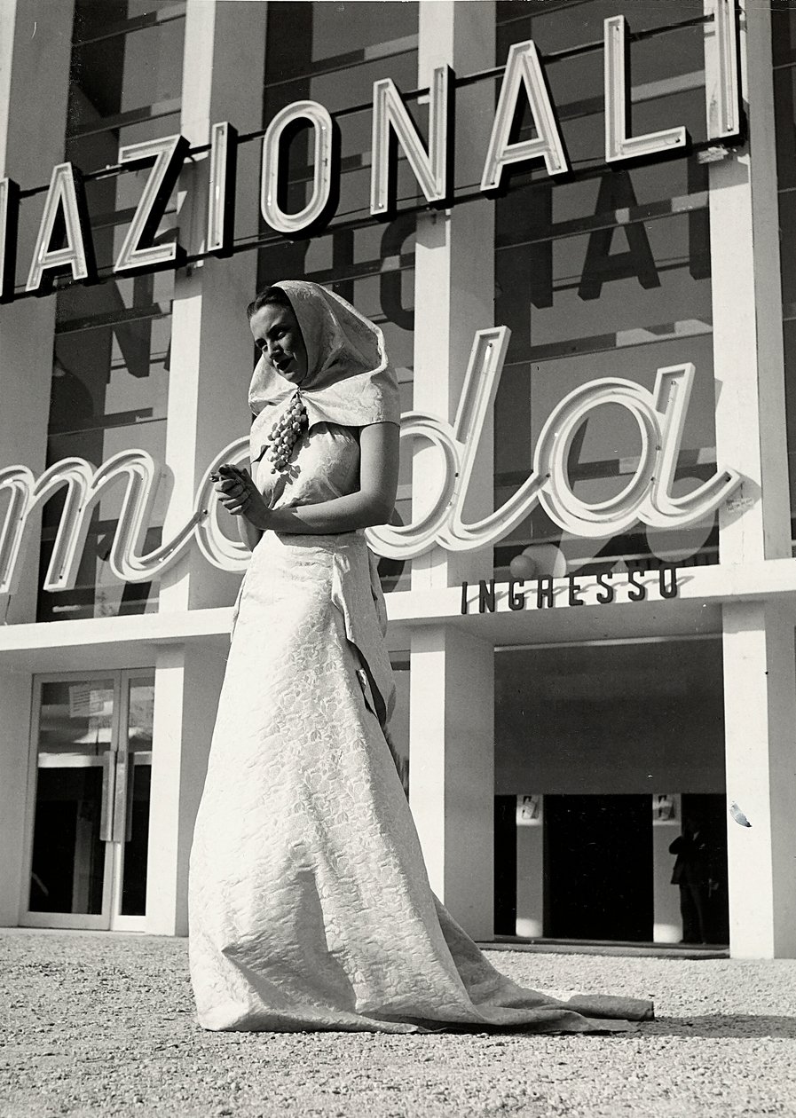 A "Lamma" couture ház által készített esküvői ruha modell. A cikket a szerzetesi stílusú fejdísz jellemzi, amelyet a nyaknál egy mutatós, szőlőfürt formájú tű tartja. (f/w fotó) alkotó: Luis Bogino