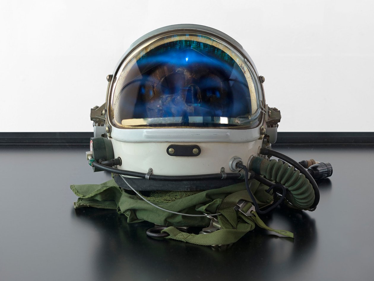 Alpha Omega, 2016 (Üveg, LCD képernyő, médialejátszó, koponyareplika, űrsisak, fa) alkotó: Mat Collishaw
