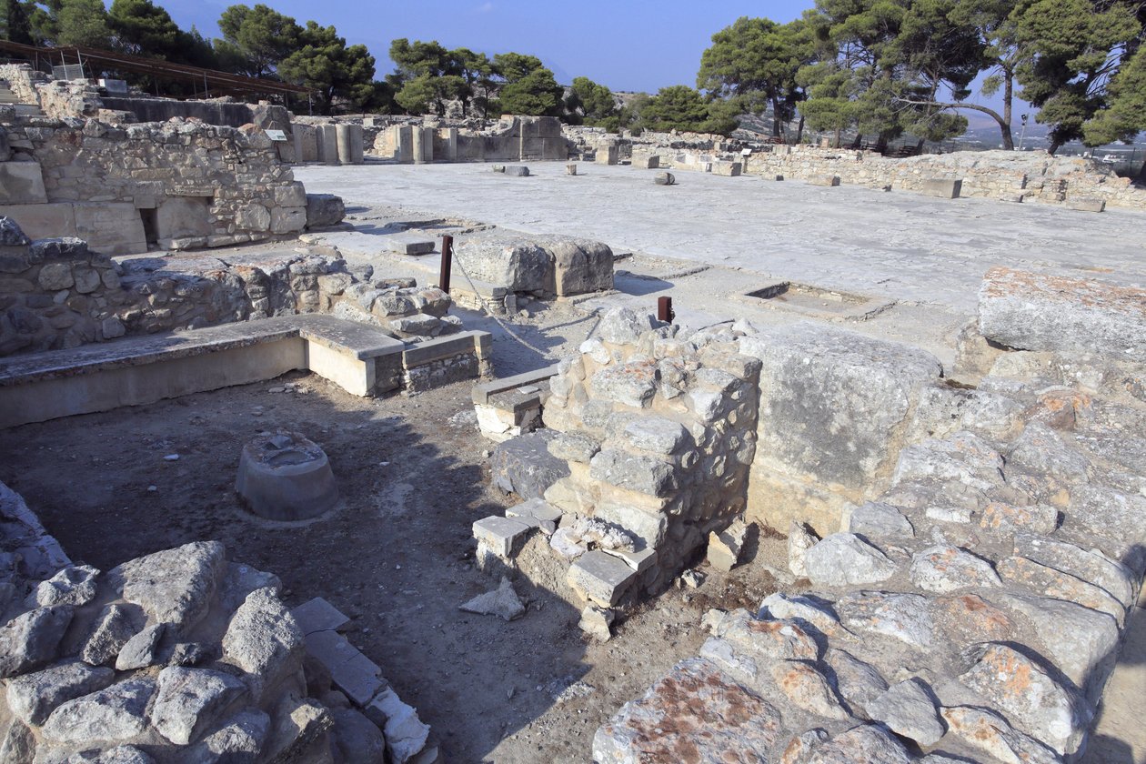 Phaistos minószi régészeti lelőhelye. Központi udvar és ""Padszentély"": kicsi és téglalap alakú szoba, a falakon alacsony padokkal, amelyek a kultikus tárgyakat és az istenség szobrát tartják. Némelyikükön női figurát, rituális edényeket, a alkotó: Minoan