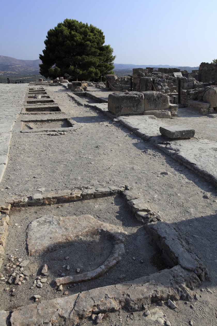 Phaistos minószi régészeti lelőhelye. A nyugati szárny szentélyeinek általános képe a központi udvar mentén az északi szárnyból. Kétféle szentély volt: „Padszentély” és „Lutrális medence”. A „pad szentély” egy kicsi és téglalap alakú szoba volt, alacsony b alkotó: Minoan