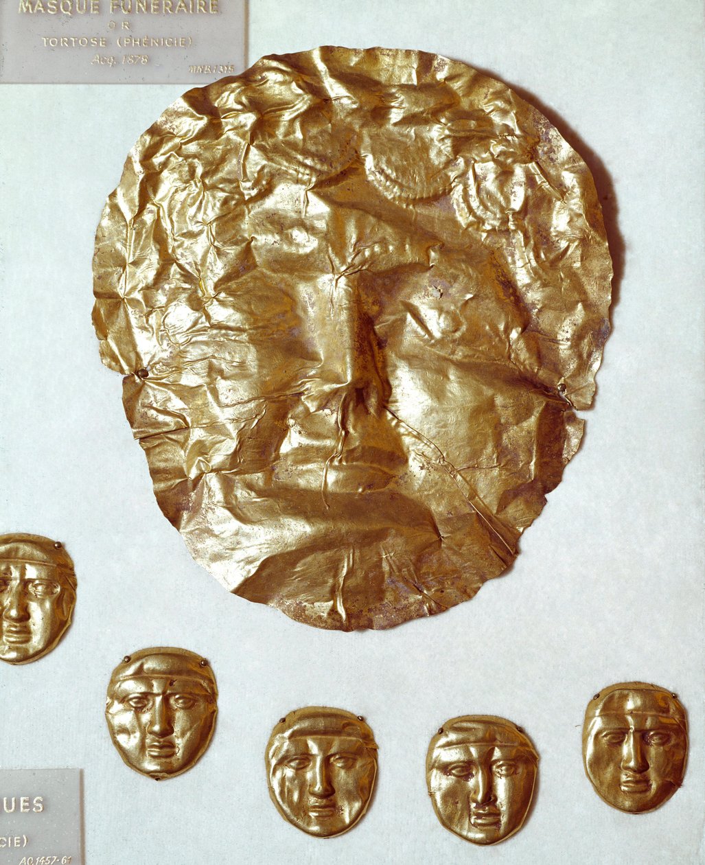 Föníciai művészet: nagy aranylevél maszk a nő arcán és öt kis arany maszk csoportja alatta alkotó: Phoenician Phoenician