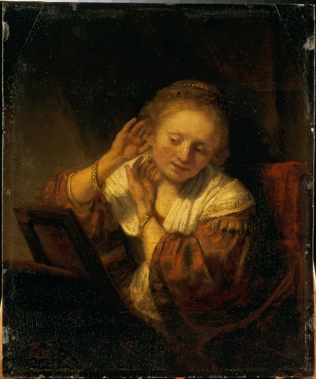 Fiatal nő díszíti magát fülbevalóval alkotó: Rembrandt van Rijn
