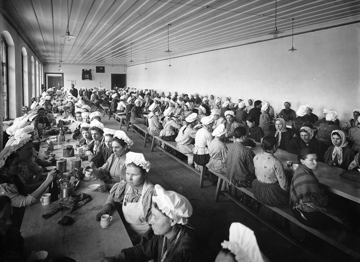 Egy gyár raktárában dolgozó női vacsoraszünetet tartanak néhány férfi felvigyázó felügyelete alatt alkotó: Russian Photographer