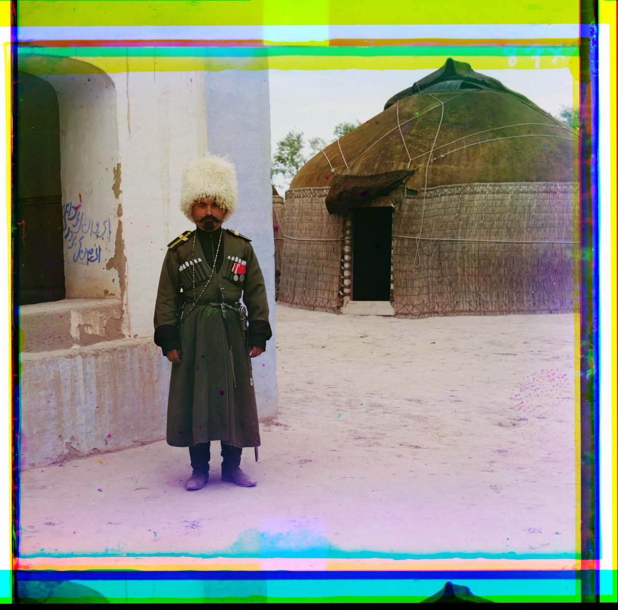 Egyenruhás fegyveres férfi áll az épület mellett, háttérben jurtával, Oroszország, 1915 alkotó: Sergey Prokudin Gorsky