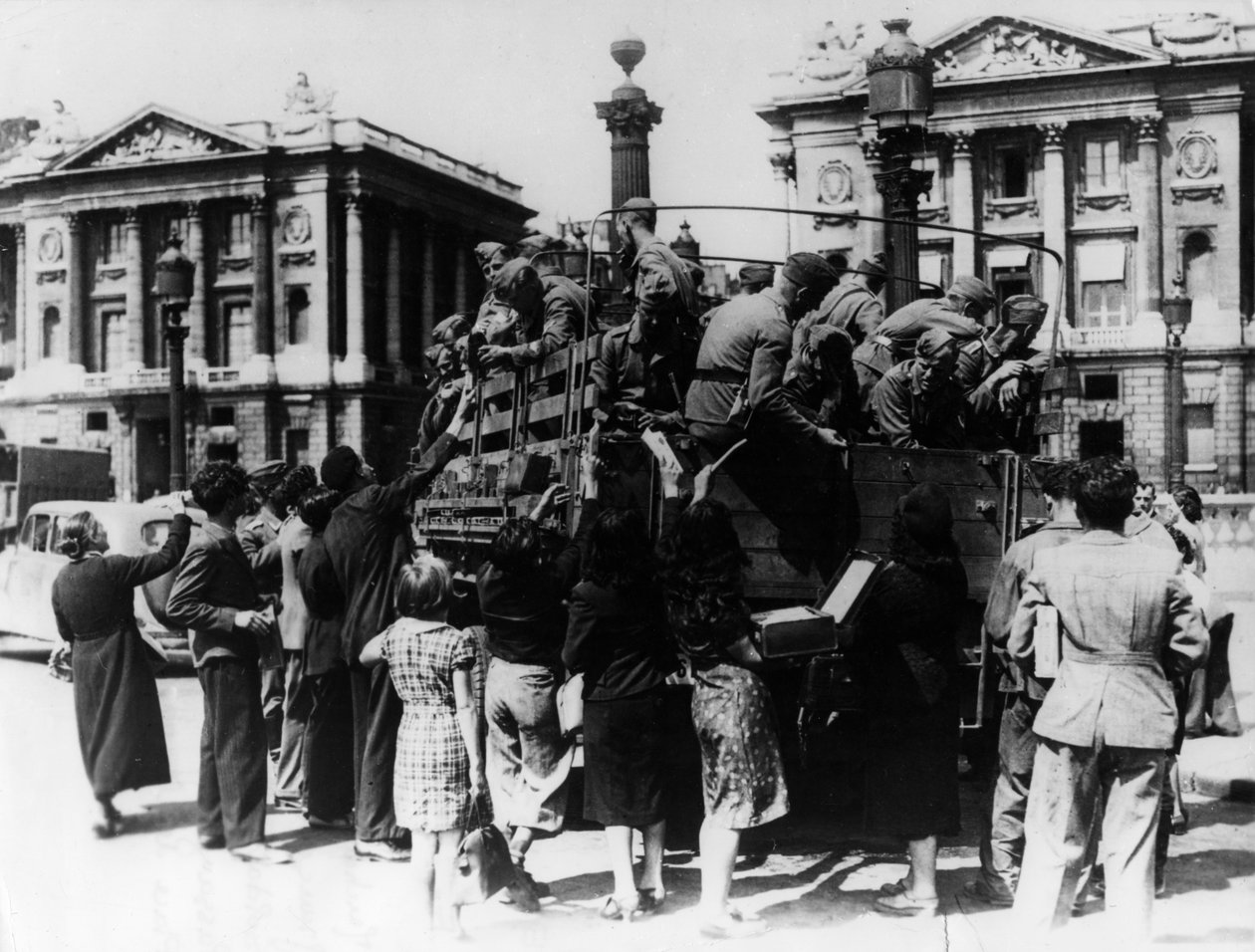 Francia utcai árusok ajándéktárgyakat kínálnak egy teherautónyi német katonának, Párizs, 1940. július 27. alkotó: Unbekannt