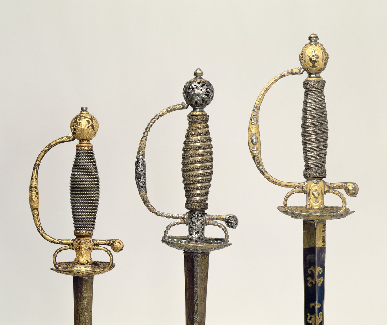 Három francia kard markolata: az egyik acélból készült, kékre festve és arany mintákkal bevonva, 1730 körül; az egyik acélból áttört és cizellált, a talaj pedig matt aranyból, 1760 körül; egy vésett acélból, gr alkotó: Unbekannt Unbekannt
