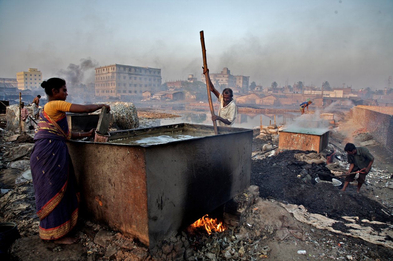 Dolgozók bőrhulladékot forralva ragasztót készítenek Hazaribagh területen, a Buriganga folyó partján, Dakkában, Bangladesben. Mint sok más iparág, amely nem törődik a környezeti tényezőkkel, a bőrgyárak is komoly károkat okoznak a környezetben. Hazar alkotó: Unbekannt Unbekannt