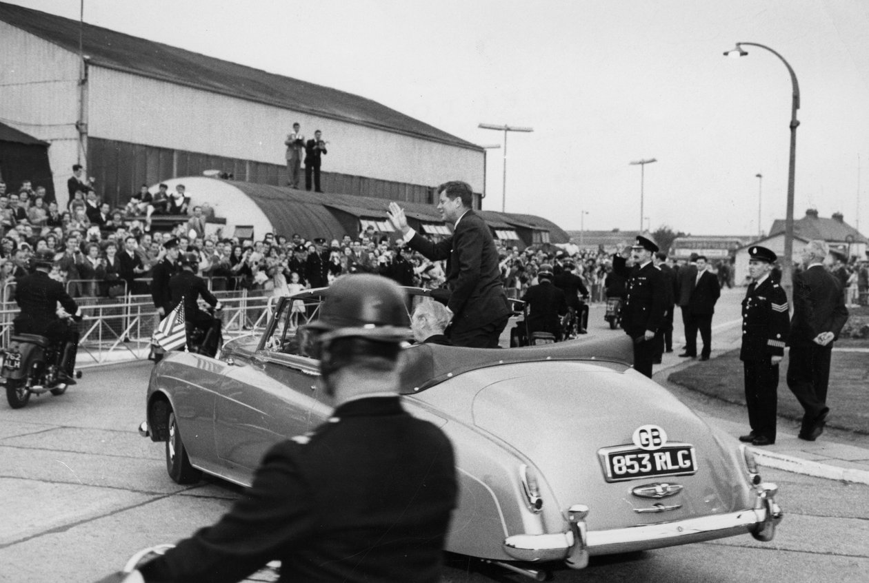 Kennedy elnök és Macmillan úr, miután megvizsgálták a londoni repülőtéren a haditengerészeti díszőrséget, egy nyitott autóval elhajtott. alkotó: Unbekannt