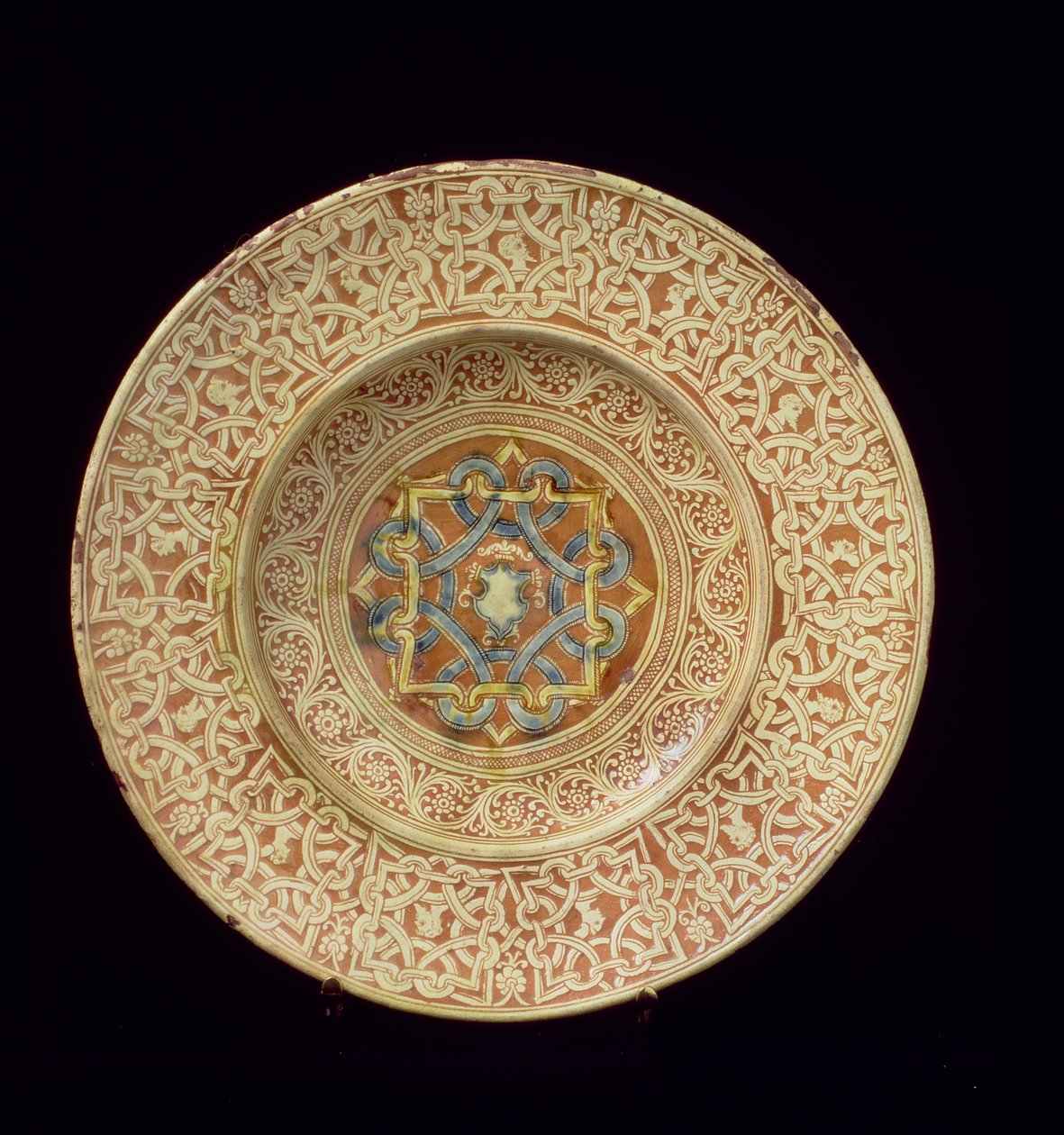 Maiolica tányér, kidolgozott, ismétlődő csomómintával díszített profilfejeket keretező szegélyen és pajzs a központi táblában, olasz, Toszkánában alkotó: Unknown