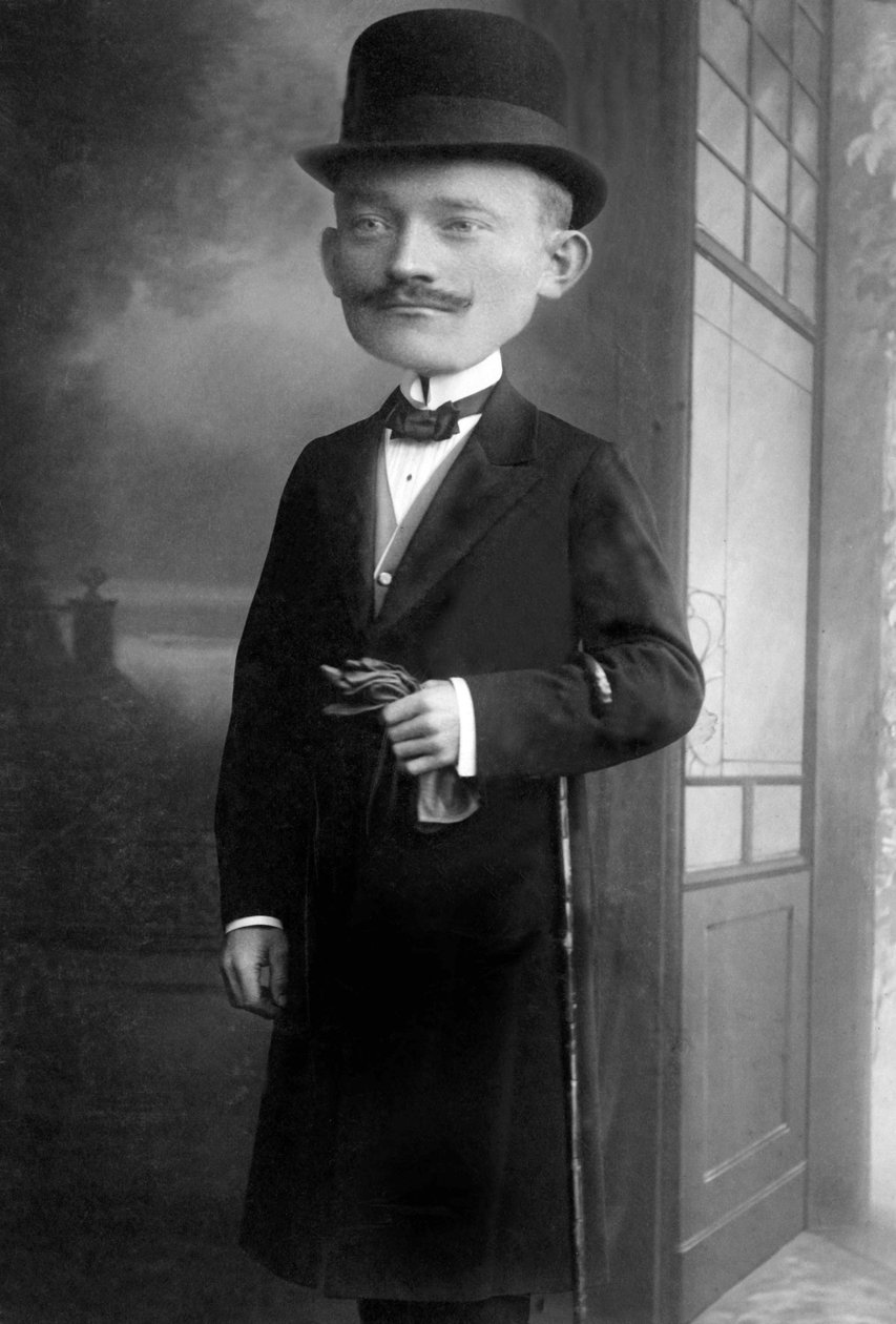 Egy nagyon elegáns, óriásfejű férfi portréja, dinnyés kalapot, botot, csokornyakkendőt és fekete kabátot visel. Ez egy fotómontázs. Annees 1910 Történelmi fénykép, óriásfejű férfi alkotó: Unbekannter Künstler