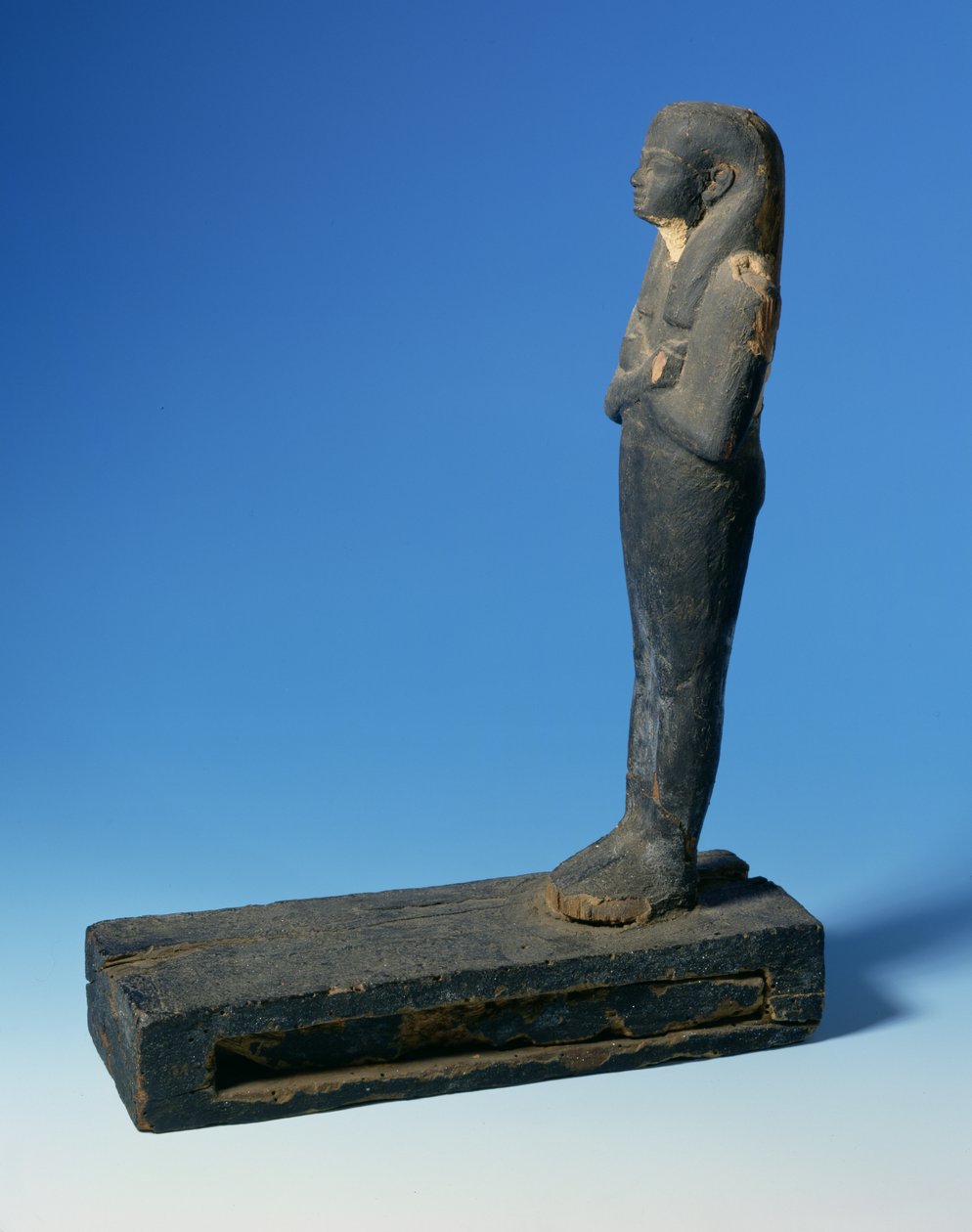 Ptah-Sokar-Osiris figura háromrészes parókával és keresztbe tett karokkal egy téglalap alakú lábazaton, papiruszszelvényt tartalmazó rekesszel (lásd: 83304), egyiptomi, 21-22. dinasztia, Kr.e. 900 körül (fa) (részletesen lásd: 83306) alkotó: Unbekannt