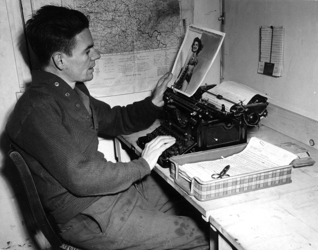 Második világháború (1939-1945) – II. világháború (II. vagy 2. világháború): Mutzig (Elzász) Franciaország 1944. december 1.: Flanerty tizedes, a Beachead News (a GI hírlapja) krónikása ránéz egy fényképre, amelyet itt tesz közzé. az újság következő száma. alkotó: Unbekannt