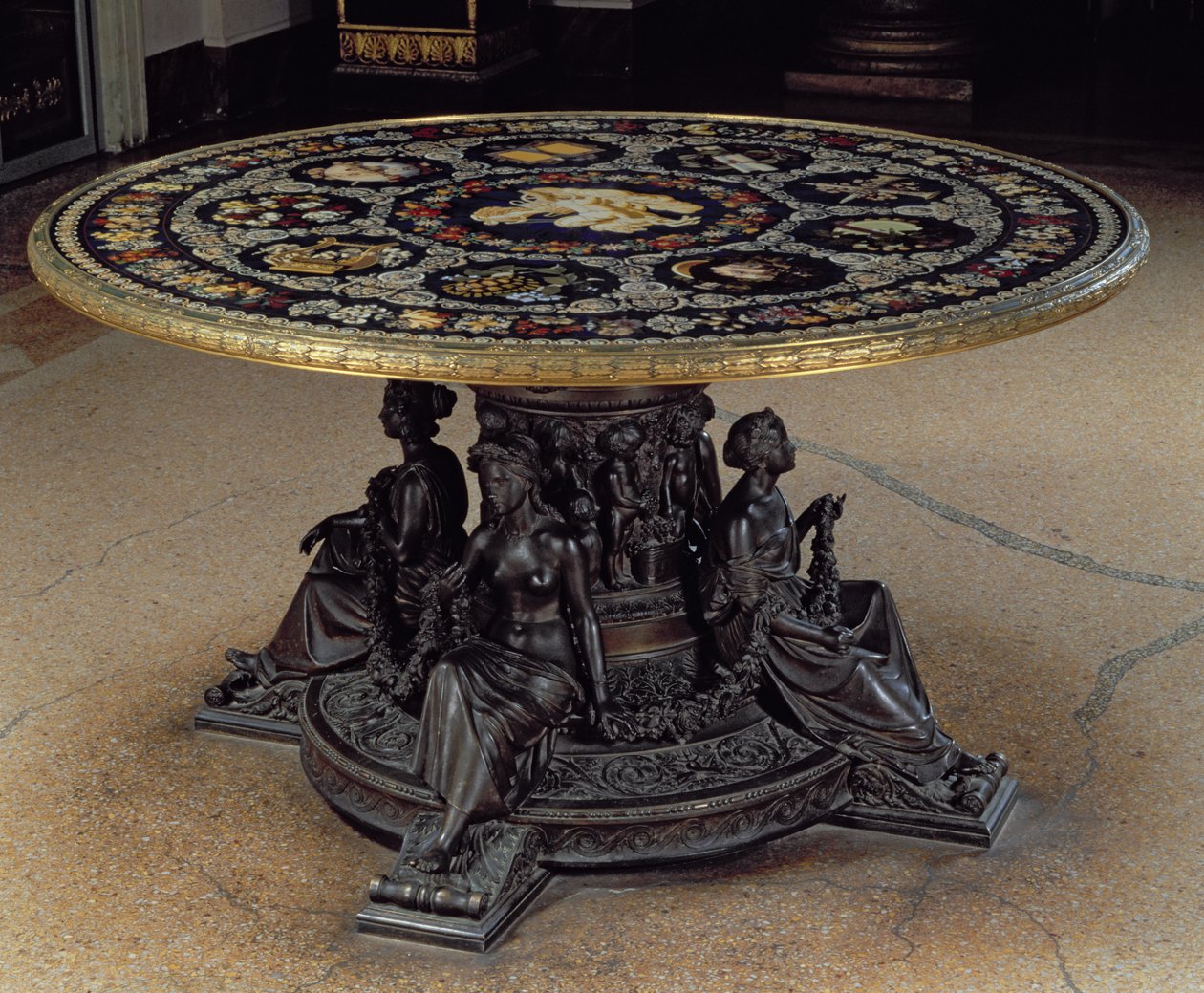 A Múzsák asztala, amely egy kör alakú pietra dura asztallapból áll, amelyet egy bronz dob támaszt meg négy bronz múzsával, firenzei alkotó: Unbekannt