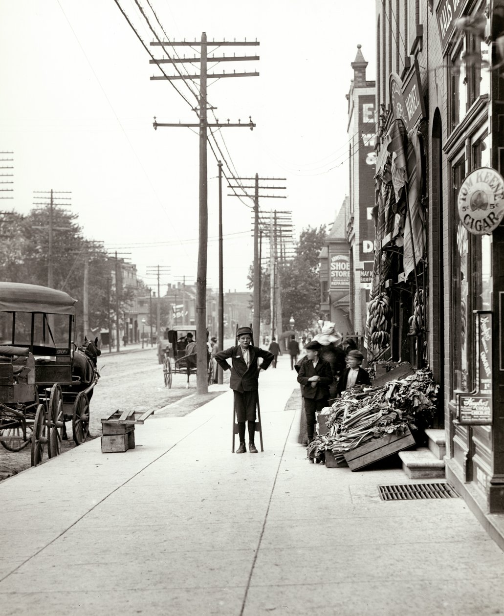 Egy gólyalábas fiú áll az F.J. Voepel piac előtt, az Easton Avenue 4874 -ben, Easton és Euclid délkeleti sarkán. Eastont később Dr. Martin Luther King Drive néven ismerték alkotó: Unknown