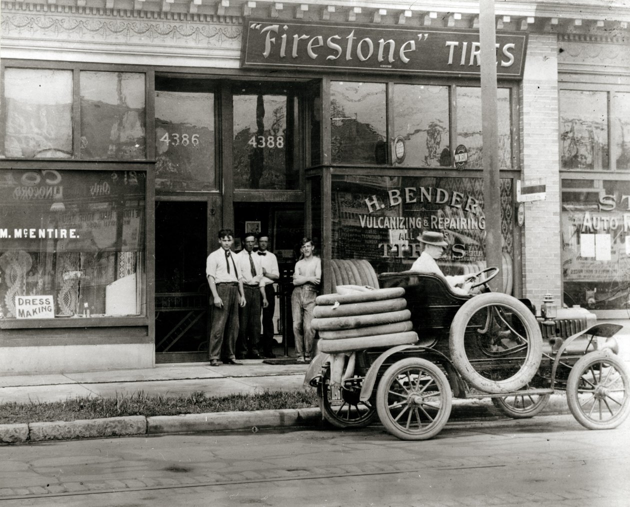Férfiak és autógumi-javító teherautó gyűlt össze a H. Bender Firestone Tire Tire kereskedés előtt, az Olive Street 4388-ban. alkotó: Unknown