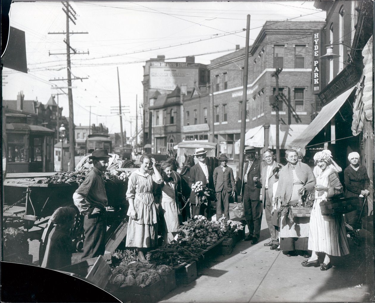 A járdán gyülekező vásárlók a Theodore Prieshoff Grocery, 1929 East Grand Avenue mellett, a Grand Avenue víztorony közelében készítenek termékeket alkotó: William G. Swekosky