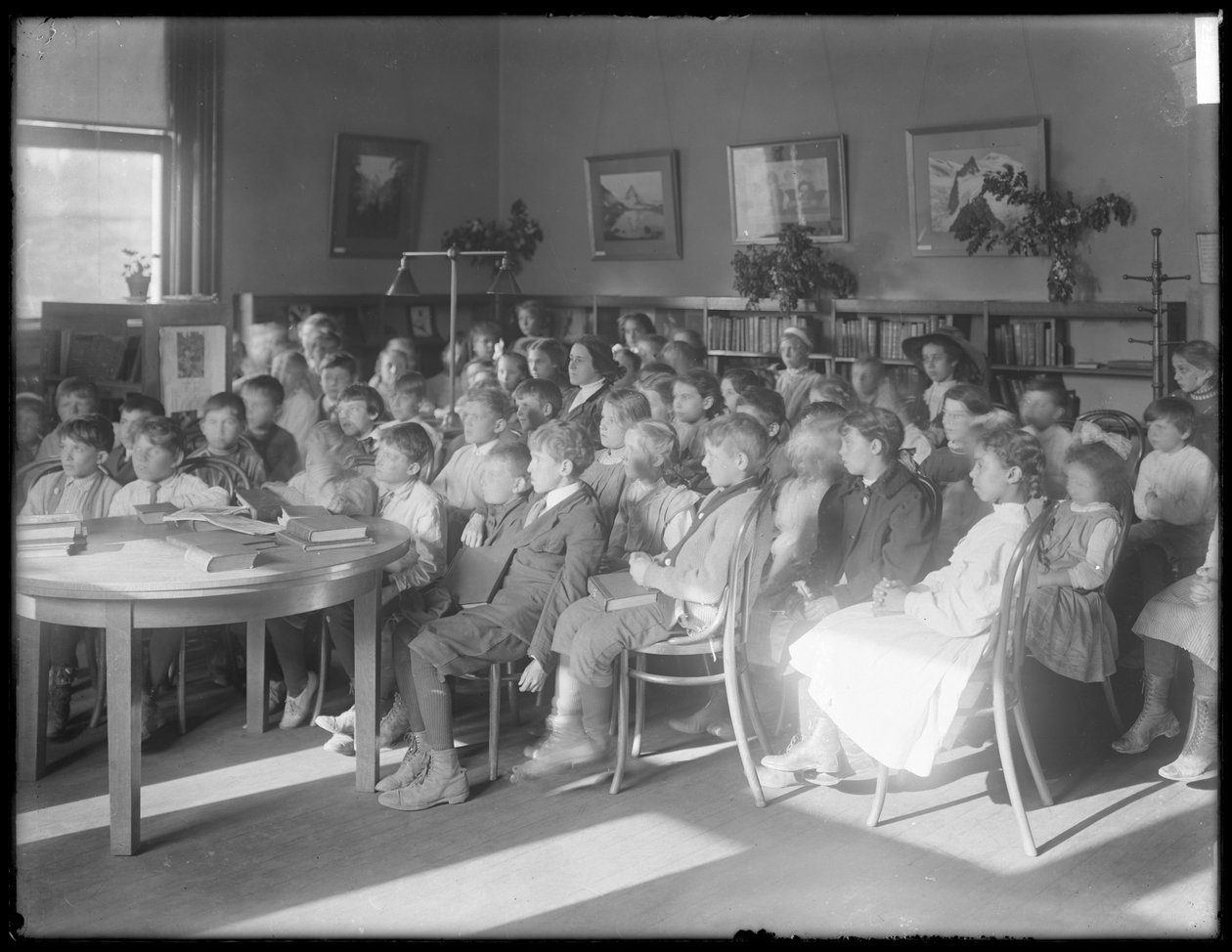 Gyerekek ülve hallgatóznak a Queens Borough Public Library egy azonosítatlan fiókjának olvasótermében, 1910 körül alkotó: William Davis Hassler