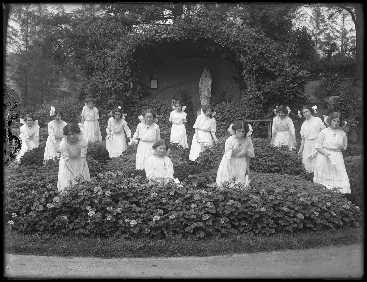 Leányok végzős osztálya a Római Katolikus Árvaszállóból a virágoskertben, a Szűz Mária barlang előtt, 1912 bw fotó alkotó: William Davis Hassler