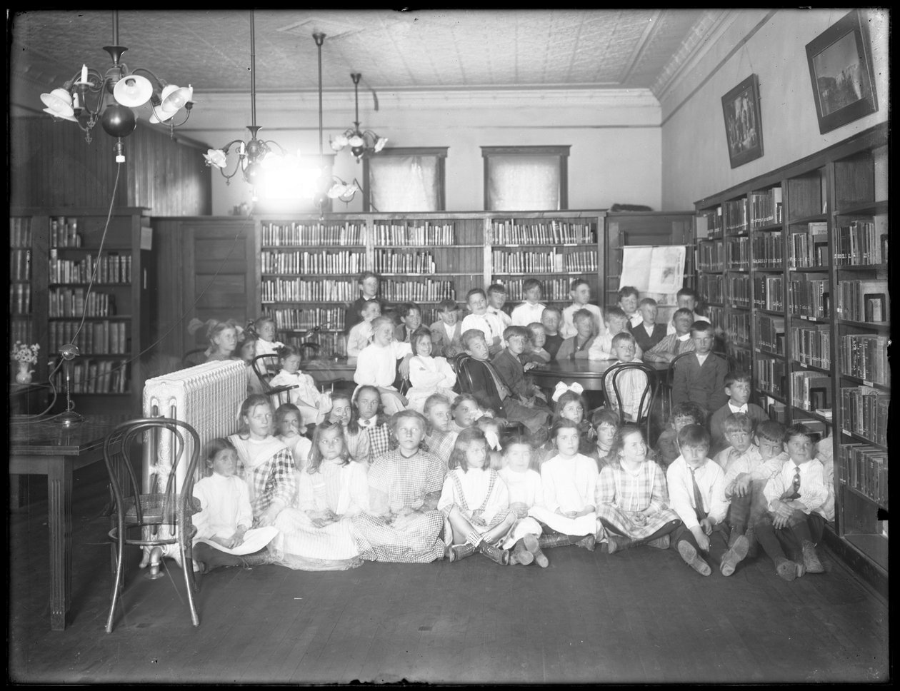 Csoportos portré gyerekekről a Queens Borough Public Library egy azonosítatlan fiókjának olvasótermében, 1910 körül alkotó: William Davis Hassler
