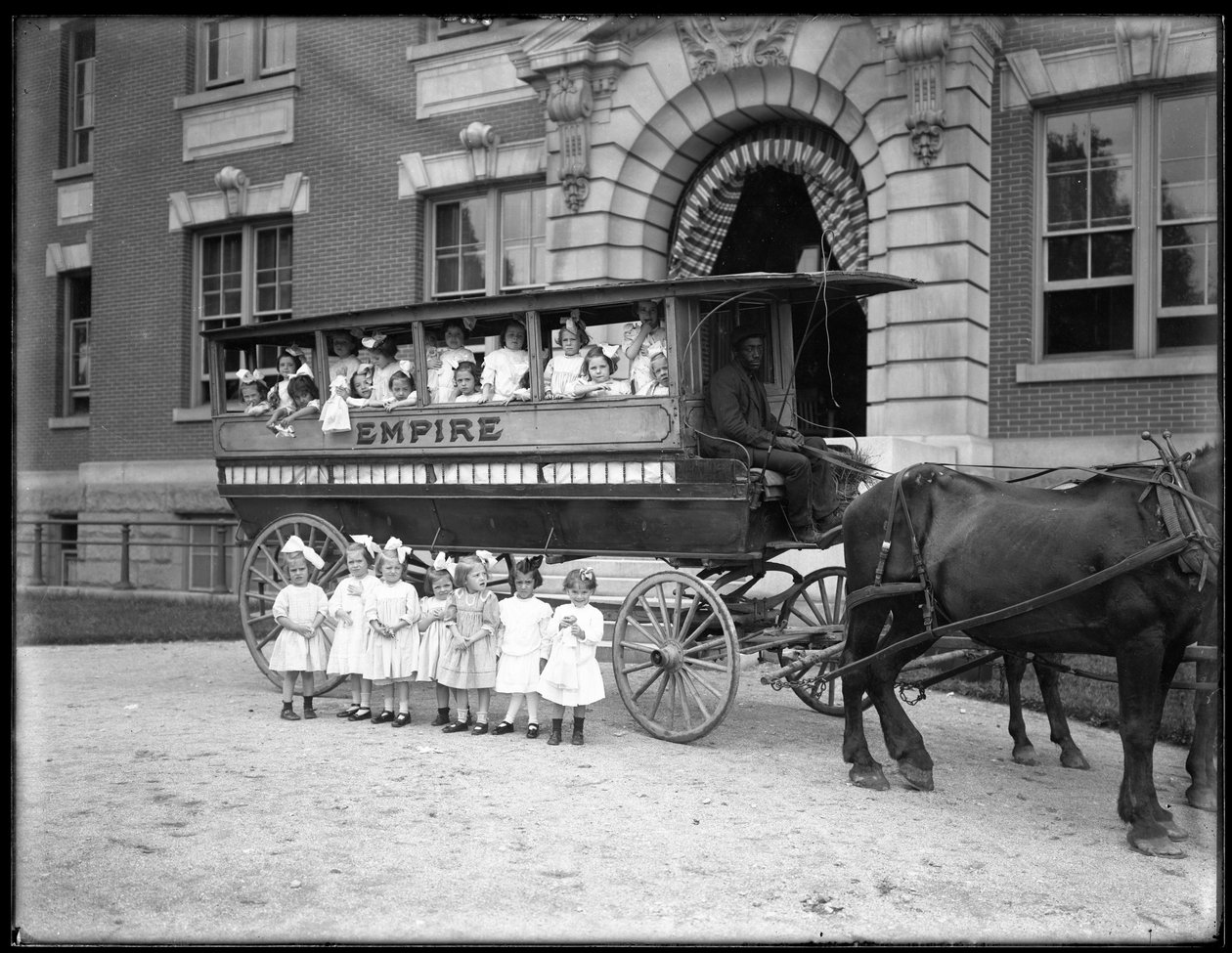 Kislányok pózolnak egy lovas kocsiban és előtte, egy ismeretlen épület előtt, valószínűleg a római katolikus árvamenhely, Kingsbridge, Bronx, 1910 körül alkotó: William Davis Hassler
