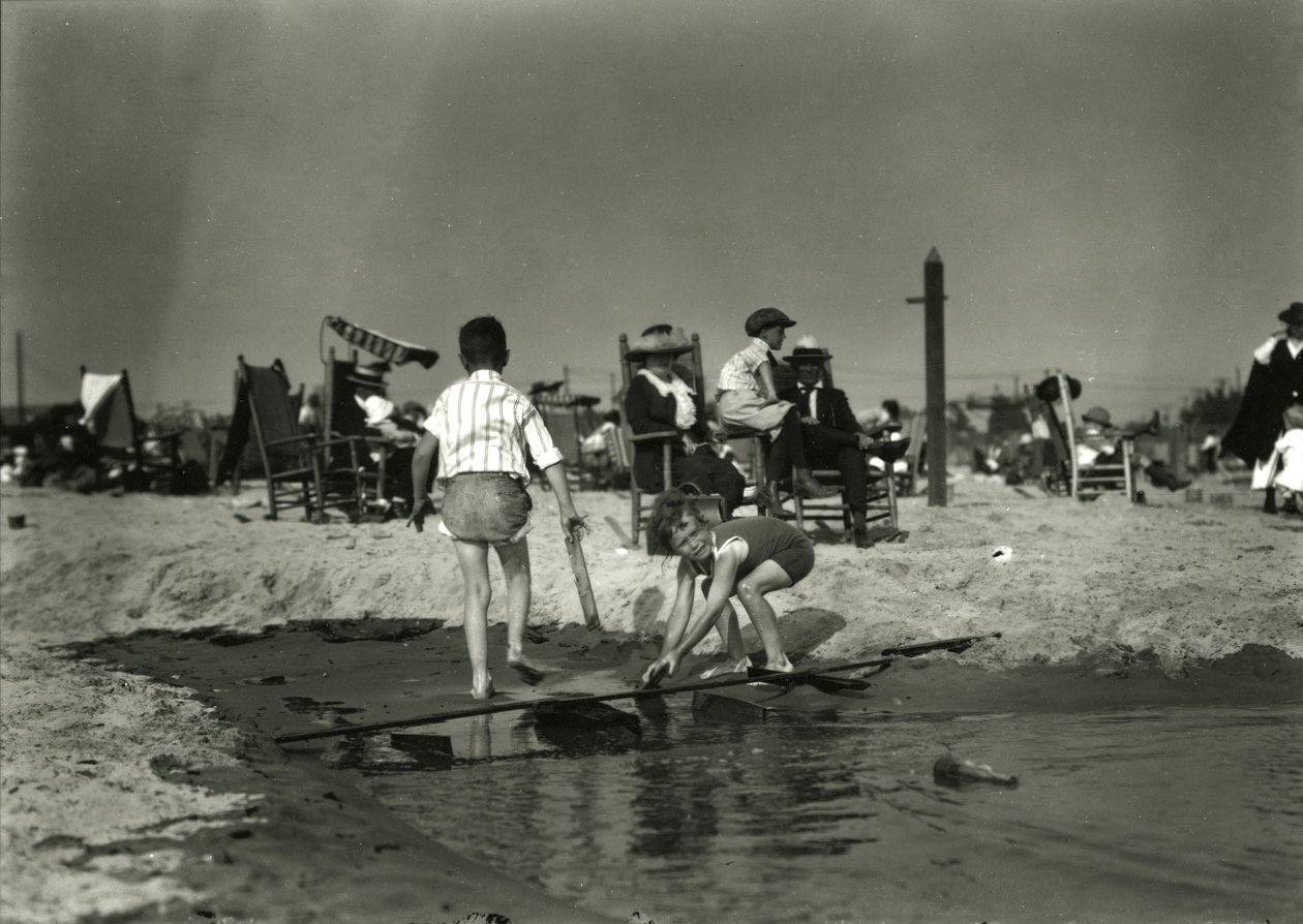 Két gyerek játszik fahulladékkal a sekély vízben, Coney Island, 1910-21 körüli évek alkotó: William Davis Hassler