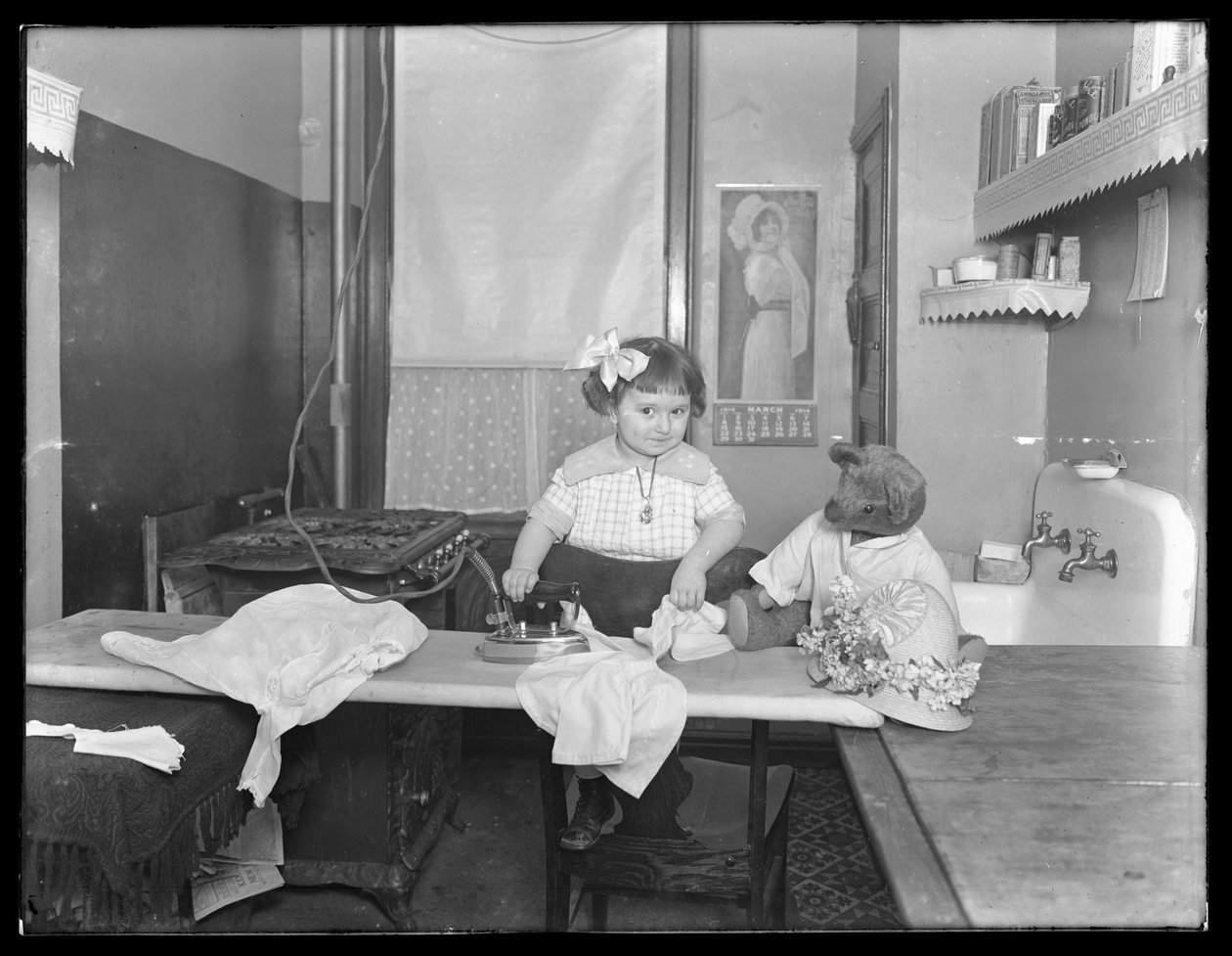 Azonosítatlan kislány elektromos vasaló használatát bemutató, 1913-14 körül alkotó: William Davis Hassler