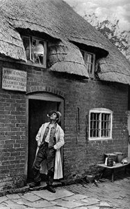 Egy férfi pipázik egy bolt előtt, Worcestershire, 1922. alkotó: A. W. Cutler